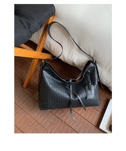 Gros plan détaillé du sac cabas noir à texture tressée avec fine bandoulière élégante