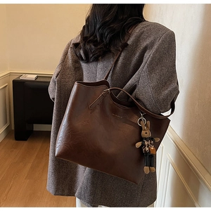 Detail view of coffee leather tote bag with gold lettering and leopard rabbit charm