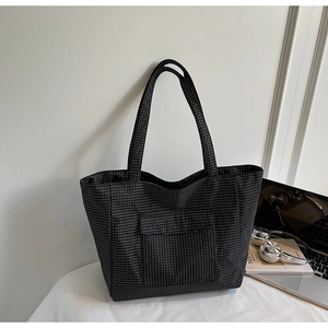 Detail of checkered tote bag with front pocket showing large capacity and canvas texture
