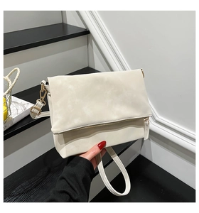 Close-up of cream rectangular shoulder bag with gold zipper detail and matte leather finish