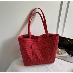 Detailed macro view of the red and white checkered canvas tote with a front flap pocket