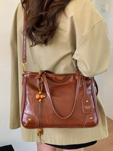 Vintage brown leather tote bag with top handles, crossbody strap and tassel charm