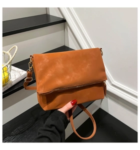Close-up of caramel leather crossbody bag with metal zipper and soft textured surface