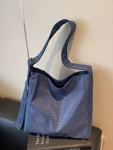 Blue plaid oxford tote bag with large capacity and adjustable strap on a leather sofa