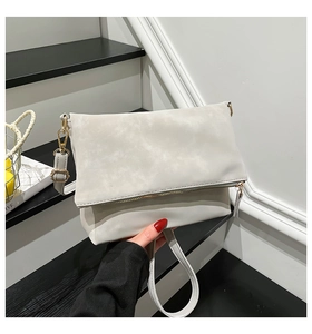 Close-up of minimalist beige shoulder bag showing matte suede texture and gold zipper