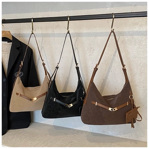 Three colors of large suede hobo tote bags displayed on a rack with metal buckles