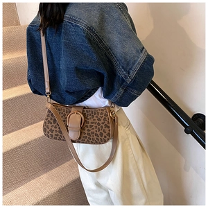 Detail of leopard print bucket bag with leather buckle and adjustable strap on a shoulder
