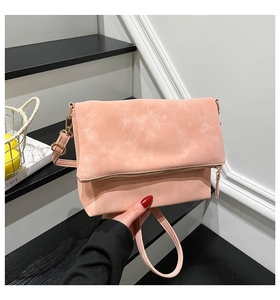 Detail of pale pink suede shoulder bag with gold zipper and thin detachable strap