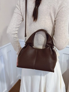 Sac seau rétro marron foncé motif litchi présenté avec un mannequin en extérieur