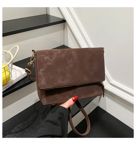 Detail of dark brown matte leather flap bag with gold zippers and adjustable strap