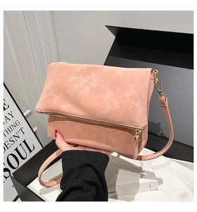 Detail of pink faux leather crossbody bag with gold zipper and adjustable shoulder strap