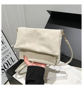 Detail of cream white faux leather crossbody bag with soft pleats and gold metal hardware