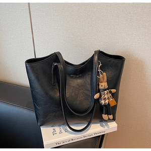 Detail of black pebbled faux leather tote bag with gold lettering and cute bunny charm