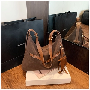 Detail of dark brown matte leather tote bag with a decorative leather elephant charm