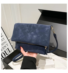 Detail of dark blue suede crossbody bag with vintage marble texture and metal zipper