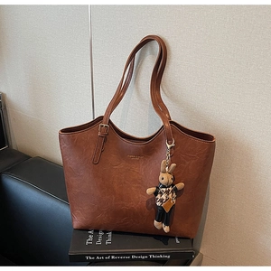 Detail of a brown tote bag with vintage lychee texture and cute rabbit charm