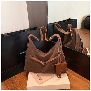 Detailed view of brown suede tote bag featuring a leather strap and elephant charm accent