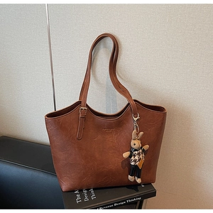 Macro shot of brown retro tote bag with embossed logo and cute rabbit charm on books