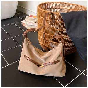 Detail view of large beige tote bag featuring brown faux leather trim and adjustable strap