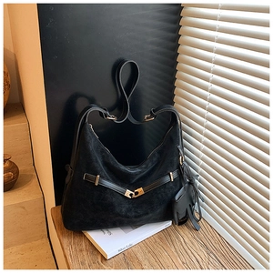 Detail of black suede hobo bag with gold buckle and cute elephant charm in soft shadows