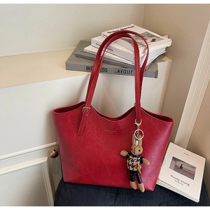 Close-up of red PU leather tote bag texture with minimalist logo and leopard bunny charm