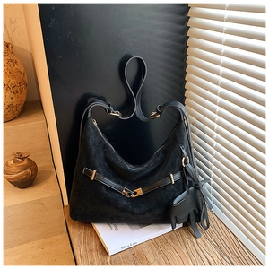 Detail of a black matte leather hobo bag with metal buckle and cat-shaped pendant charm