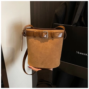 Detail view of vintage brown suede bucket bag featuring a decorative belt buckle and strap