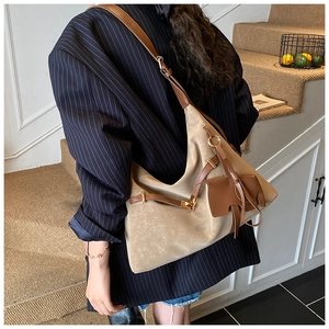 Close-up of beige oversized tote bag featuring a leather elephant charm and brown straps