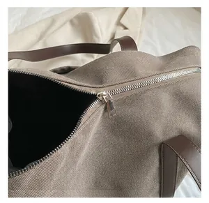 Dettaglio di cerniera in metallo e manico in pelle marrone su borsa in tela grande