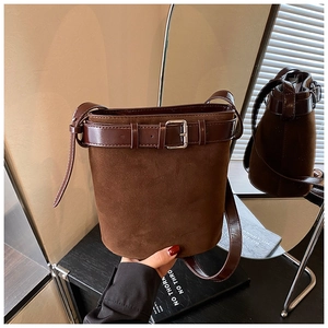 Detail of suede bucket bag with leather belt buckle and silver metal hardware accents