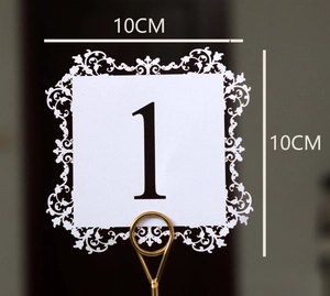 Detail of laser-cut wedding table number card with lace border and gold metal holder