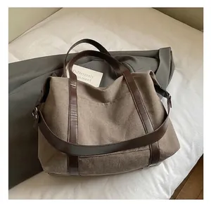 Dettaglio della borsa tote in tela marrone vintage con manici in pelle e cuciture fini