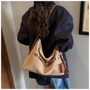 Detail view of khaki tote bag with dark brown leather strap and leaf charm on model