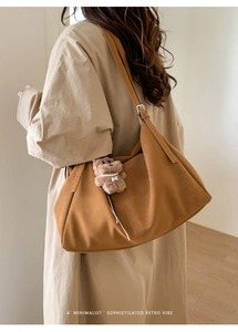 Detalle de bolso tote de ante marrón con un lindo colgante de osito de peluche beige