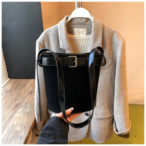 Detail view of black suede bucket bag with silver buckle and leather strap details