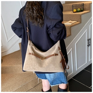 Rear view of a model wearing a large beige tote bag with brown leather straps