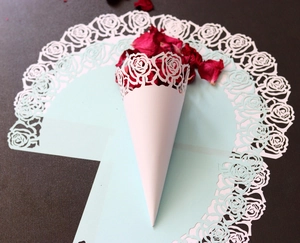 Détail du cône de mariage en papier découpé au laser avec roses et pétales rouges