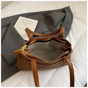 Detailed top view of brown textured PU tote bag featuring a golden zipper and spacious interior