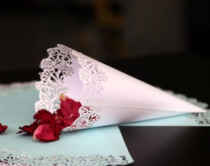 Detailed macro view of laser-cut white paper cone with delicate rose lace pattern for weddings