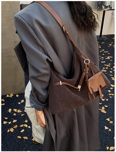 Detail of dark brown tote bag featuring unique elephant charm and adjustable shoulder strap