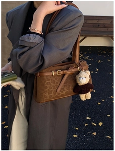 Detail of leopard print bucket bag featuring a decorative buckle and teddy bear charm