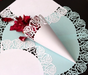 Détail de cornet à confettis en papier blanc ajouré au laser avec motif rose de mariage