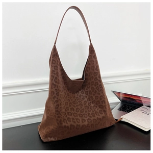 Detail of leopard print hobo tote bag texture on a desk with a notebook and laptop