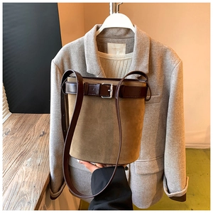 Detail of suede bucket bag featuring contrast leather strap and silver buckle closure