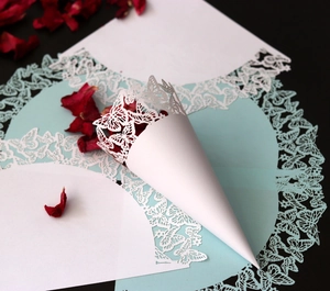 Detail of white laser-cut butterfly paper confetti cones with lace design for weddings