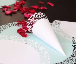 Detail showing laser-cut lace pattern on white paper cone for wedding petals