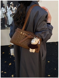Detail of leopard print bucket bag with buckle strap and cute teddy bear charm
