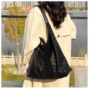 Chic black leopard print tote bag styled by the river with a modern city background
