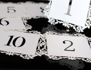 Detail view of elegant table number cards with ornate black lace border for wedding banquets