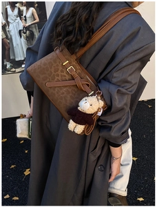 Detail view of leopard print bucket bag with brown leather strap and cute bear charm